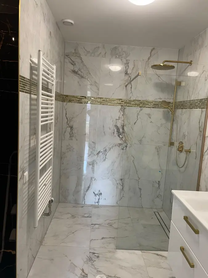 Badkamerrenovatie — Inloopdouche met marmerlook tegels, goudkleurige regendouche en handdoekradiator