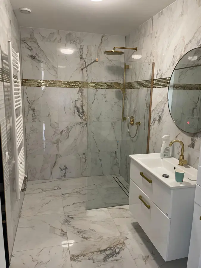 Badkamerrenovatie — Badkamer met inloopdouche, wastafelmeubel en goudkleurig kraanwerk in marmerlook