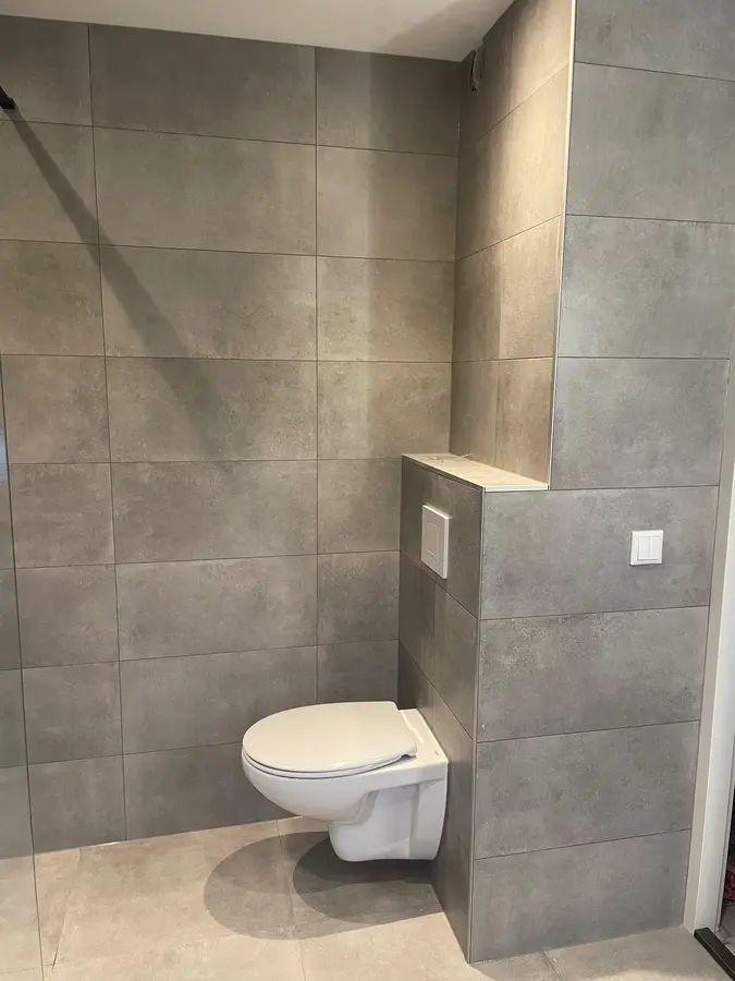Sanitair & kranen — Hangend toilet met inbouwreservoir tegen een betonlook tegelwand