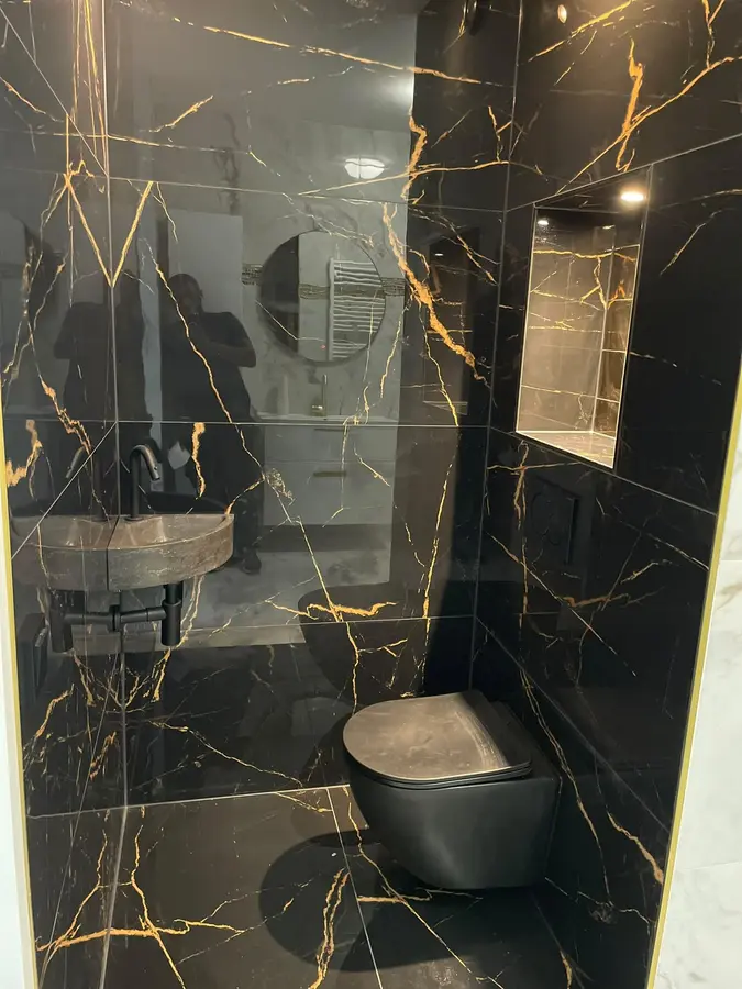 Sanitair & kranen — Toilet met zwarte marmerlook tegels met gouden aders, hangend toilet en fonteintje