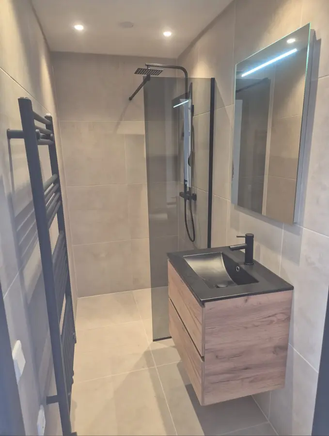 Badkamerrenovatie — Smalle badkamer met inloopdouche, houten wastafelmeubel en spiegel met verlichting