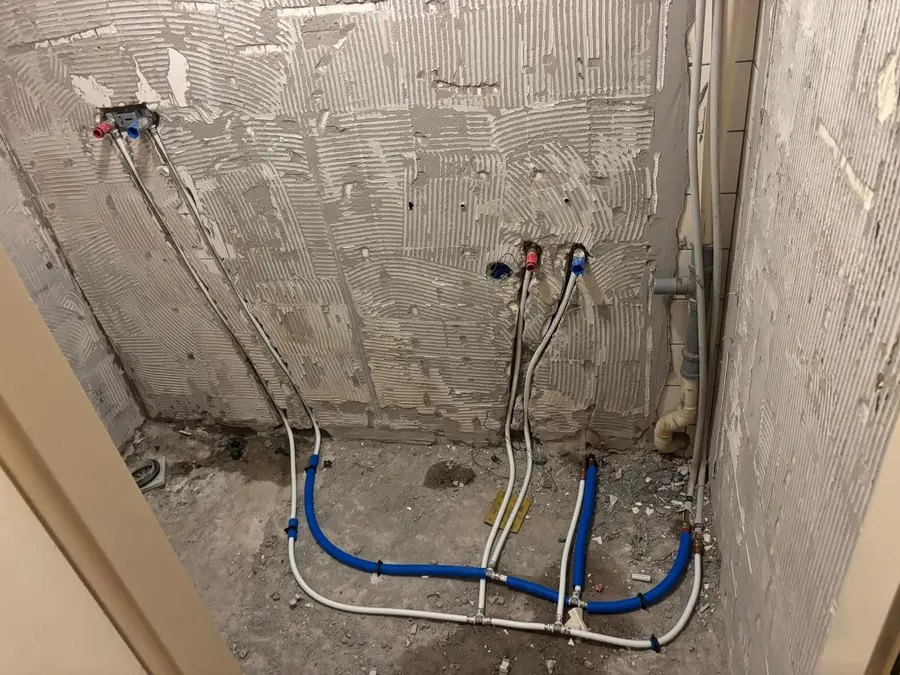 Waterleiding — Gestripte badkamerwand met nieuwe warm- en koudwaterleidingen