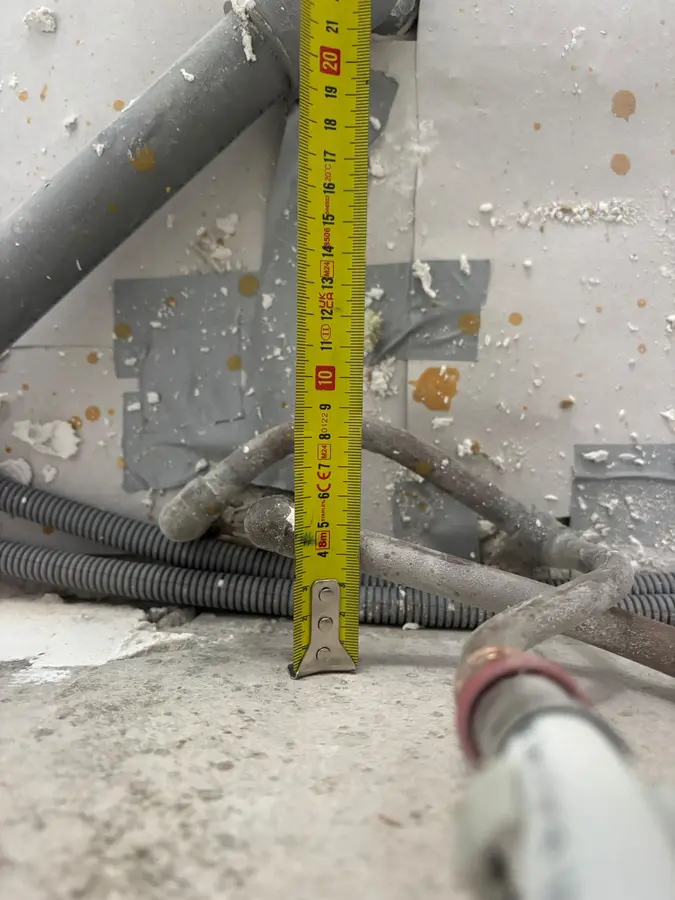 Waterleiding — Leidingen achter een wand, met meetlint voor de maatvoering