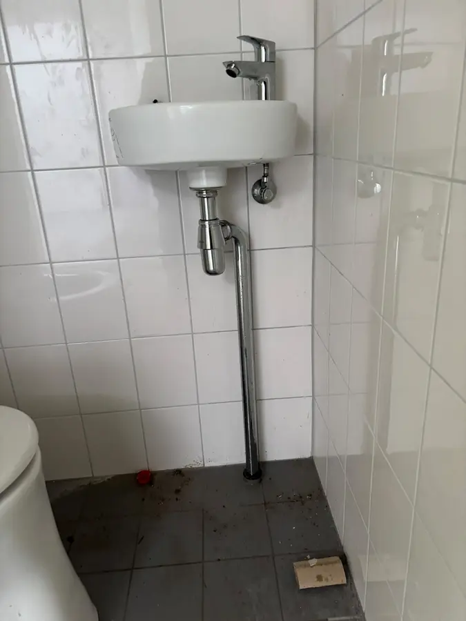 Sanitair & kranen — Fonteintje met sifon en afvoerleiding naast een toilet