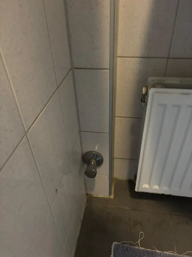 CV & verwarming — Radiator met aansluitleiding tegen een betegelde wand