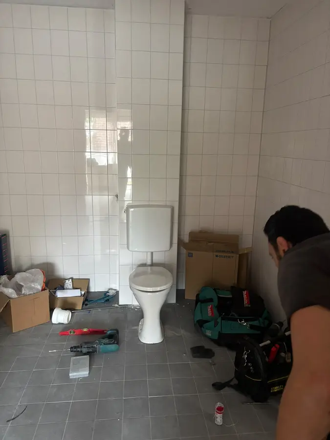 Sanitair & kranen — Monteur aan het werk in een ruimte met toilet en gereedschap