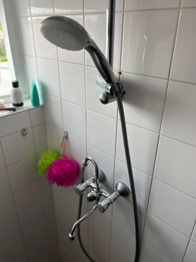 Badkamerrenovatie — Douchekraan met handdouche en glijstang tegen betegelde wand