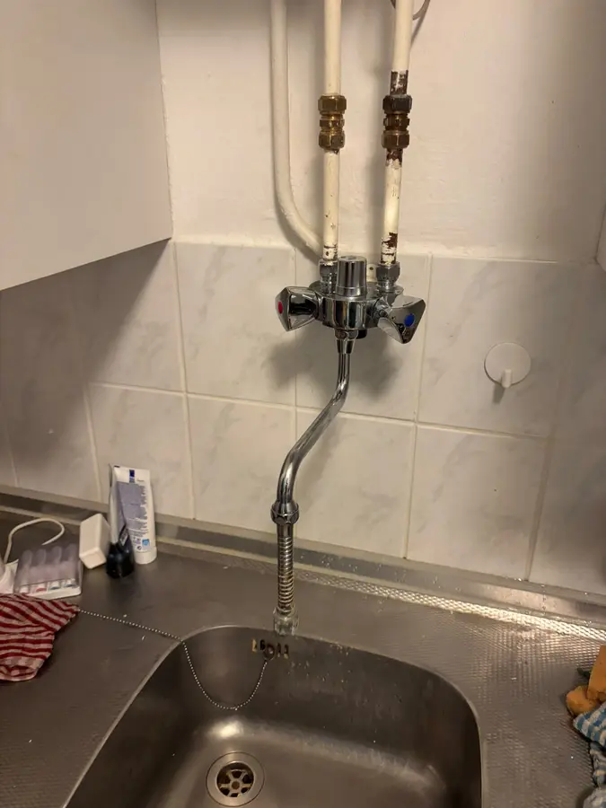 Sanitair & kranen — Keukenkraan met aan- en afvoerleidingen boven de spoelbak