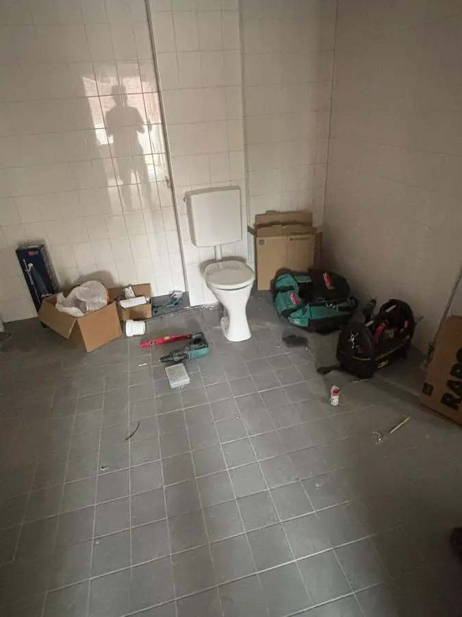 Sanitair & kranen — Ruimte in verbouwing met een losstaand toilet en gereedschap