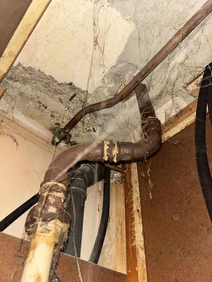 Waterleiding — Blootgelegde oude leidingen achter een weggehaalde wand