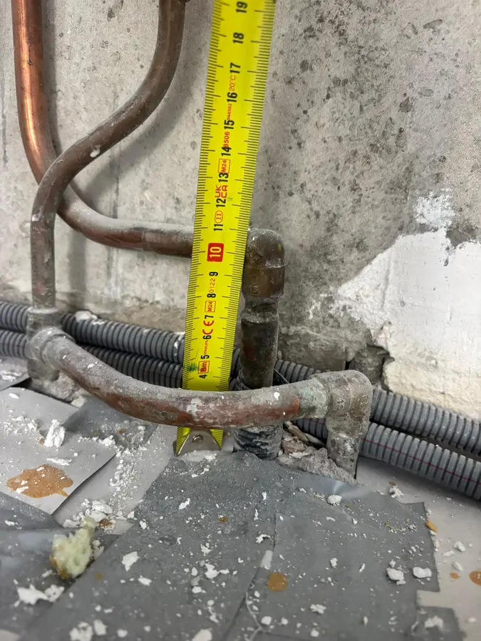Waterleiding — Koperen leidingen langs een muur, met meetlint voor de maatvoering