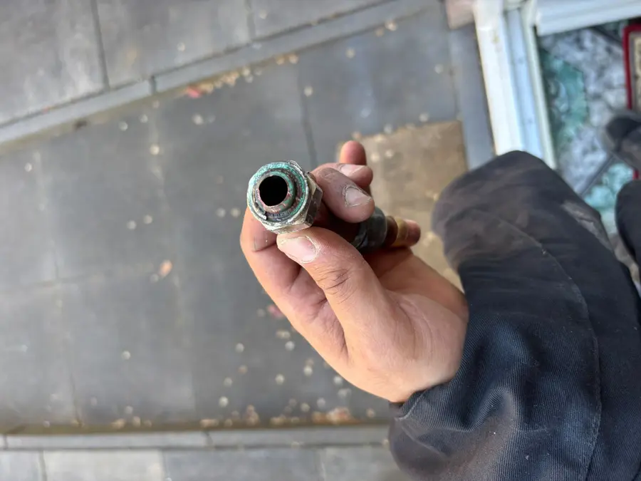 Lekdetectie — Afgezaagd stuk leiding met kalkaanslag, in de hand getoond