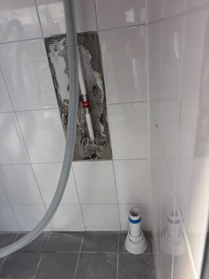 Waterleiding — Uitgehakte sleuf in een betegelde wand met nieuwe leiding